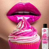 A close-up image showcases glossy pink lips with bright pink liquid dripping onto a cupcake adorned with matching pink and white frosting and sprinkles. In the corner, a small bottle labeled "Wet Desserts 'Frosted Cupcake' Lubricant 🧁" by Wet is visible, suggesting a flavored sugar-free lubricant.